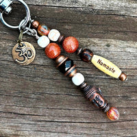 Handcrafted yoga charm with inspirational text and elegant beaded details, ideal for zippers or bags. With Buddha bead and aum charm for purses and yoga bags