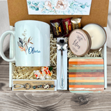 gift basket with a personalized natural foilage coffee mug, engraved spoon, vibrant coaster, scented candle, artisan charm, and coffee treats for women’s present